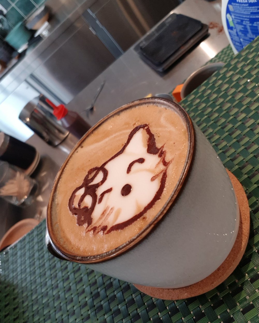 A cappuccino with chocolate latte art on the stainless-steel counter