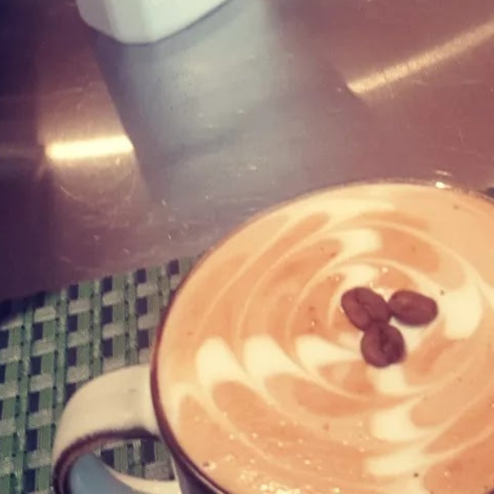A cappuccino with rosetta latte art and three coffee beans on top