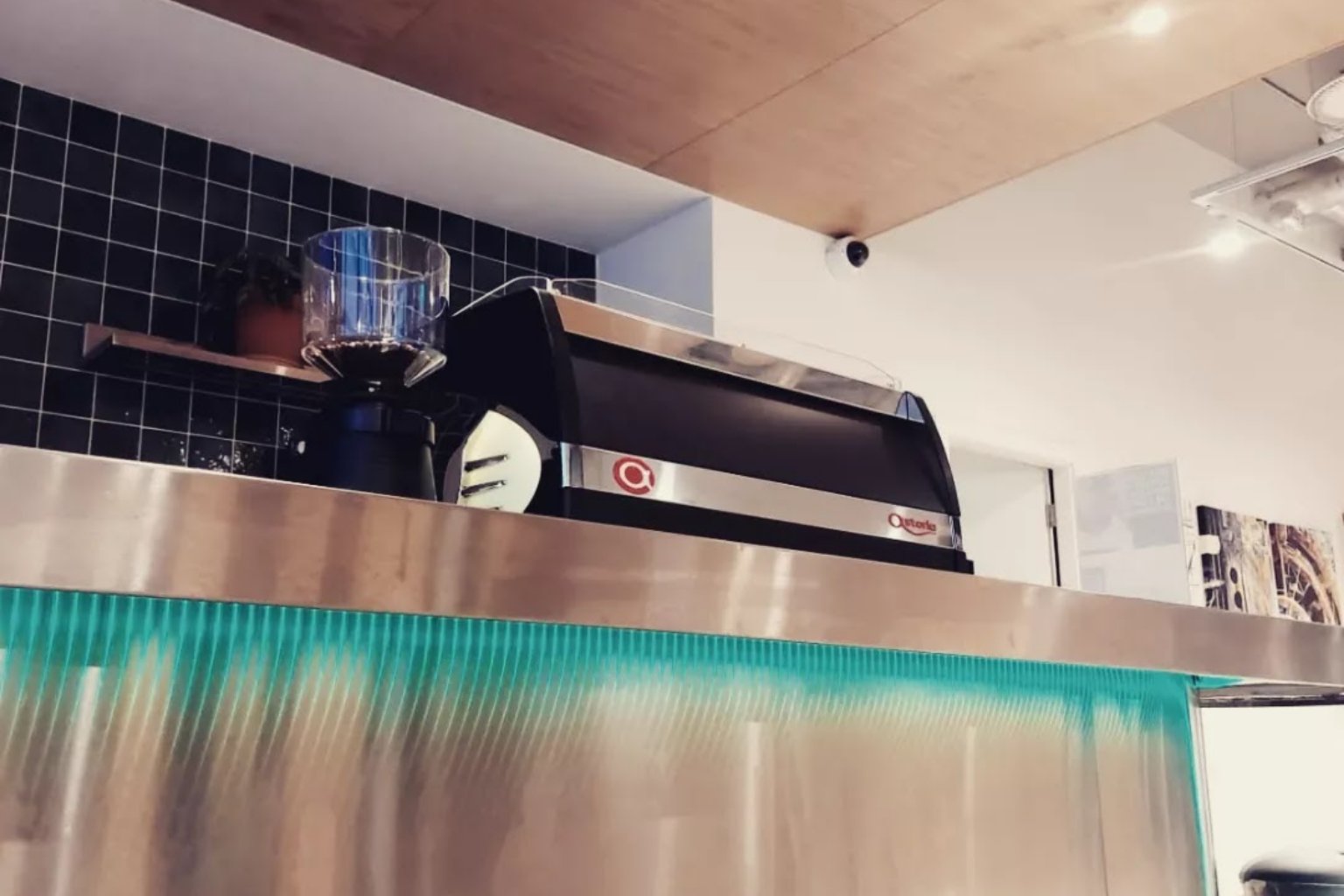 The espresso machine on the stainless-steel counter at Mellow Mood Cafe, lit by a turquoise strip under the counter edge